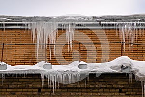 Sharp icicles hanging on the edge of the roof. Melting snow forms icicle