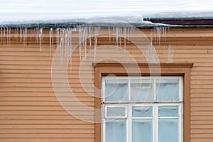 Sharp icicles hanging on the edge of the roof. Melting snow forms icicle