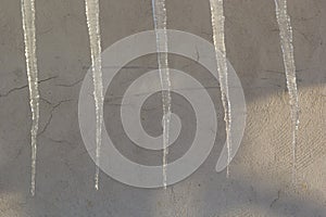 Sharp icicles and melted snow hanging from eaves of roof. Beautiful transparent icicles slowly gliding of a roof