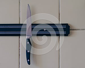 A sharp knife is attached to a magnet attached to the kitchen wall