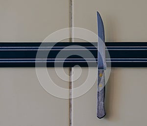 A sharp knife is attached to a magnet attached to the kitchen wall