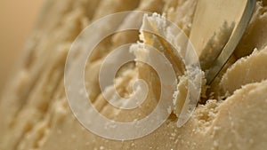 A sharp knife shreds hard cheese into small pieces. Parmesan.Very beautiful studio shot. Camera Phantom Flex.