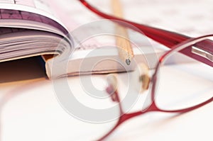 Sharp pencil in focus, eyeglass and crossword.