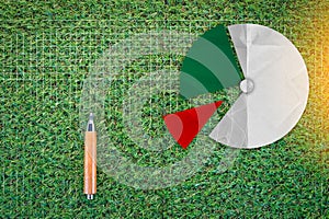 Sharp pencil and pie chart on green grass texture background