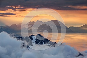 Sharp ridges above sea of clouds illuminated by rising red sun