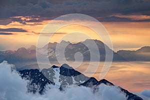 Sharp ridges of Slovenian Alps rise above orange sea of clouds