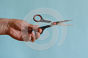 Sharp scissors with black and red arms in a male hand
