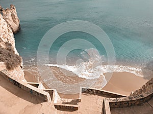 A sharp stairs lead to the the warm cerulean sea and the mild sand among the ridiculously shaped rocks