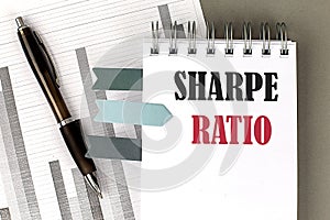 SHARPE RATIO text on notebook with pen, calculator and chart on a grey background