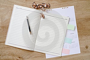 sharpen black pencil with notebook and calendar on wooden desk