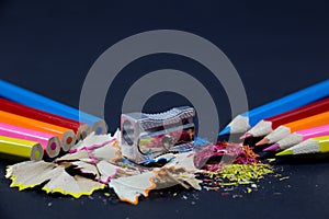 Sharpened Colorful Pencils Against Blunt Pencils with Metallic Pencil Sharpener and Colorful Pencil Shavings on Black