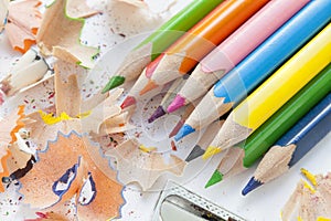 Sharpened colorful pencils, wood shavings and sharpener, closeup