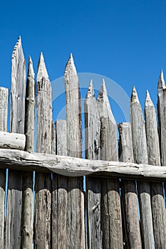Sharpened fence posts against blue sky