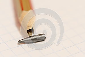 Sharpened pencil with a broken tip over a blank sheet of paper