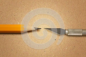 Sharpened pencil versus blade of craft knife on recycled paper background - Concept of precision and creativity