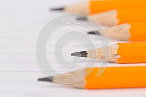 Sharpened pencils lying on a notebook sheet in a strip