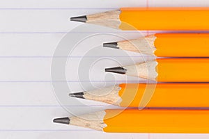 Sharpened pencils lying on a notebook sheet in a strip