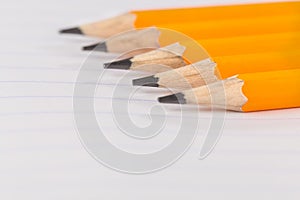 Sharpened pencils lying on a notebook sheet in a strip