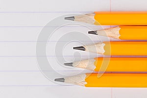 Sharpened pencils lying on a notebook sheet in a strip