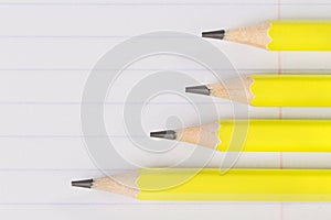 Sharpened pencils lying on a notebook sheet in a strip