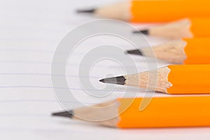 Sharpened pencils lying on a notebook sheet in a strip