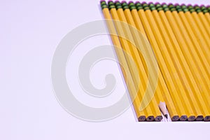 Angle of sharpened pencil in line of unsharpened pencils on white background with copy space