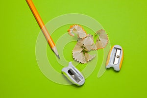 Sharpeners and pencil on green background, top view