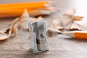 Sharpeners, pencils and shavings on wooden table, closeup