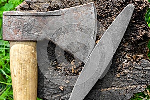 Sharpening an ax with a whetstone. Ax and grindstone on a stump.