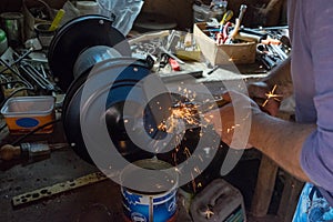 sharpening a chisel on grinding machine with sparks fly