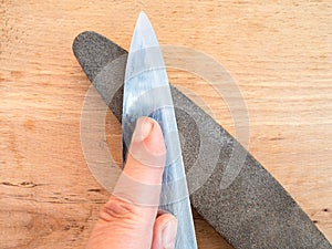 Sharpening kitchen knife closeup on whetstone