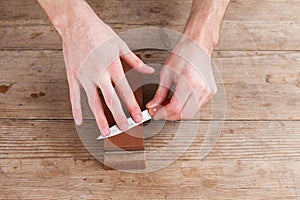 Sharpening the knife with a whetstone on a wooden background. Top view.