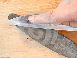 Sharpening steel knife close up on whetstone