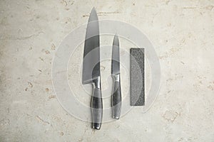 Sharpening stone and knives on grey table, flat lay