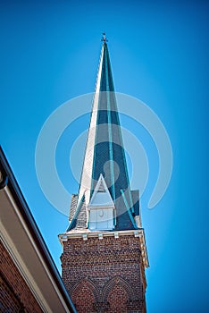 A sharply pointed church steeple against a clear blue sky.