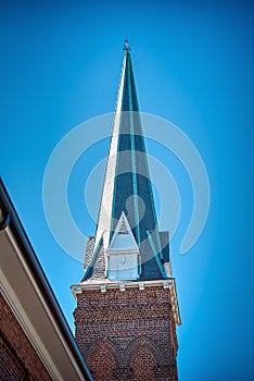 A sharply pointed church steeple against a clear blue sky. photo