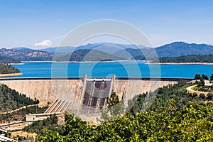 Shasta Dam on a sunny day; the summit of Mt Shasta covered in snow visible in the background; Northern California