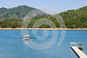 Shasta Lake, McCloud River Arm landscape on a sunny summer day with ship approaching the shoreline, Northern California