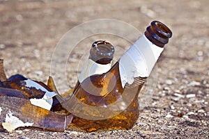 Shattered beer bottle resting on the ground - alcoholism concept