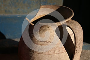 Shattered clay jug. Broken clay pot on on the steps of a house with blue door fragment. Hard light