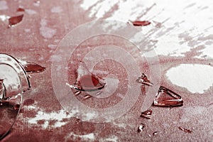 Shattered glass from a broken glass on a tablecloth drenched in red wine