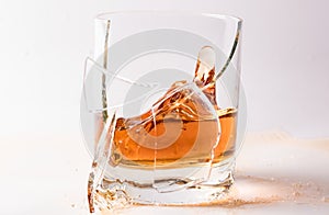 A shattering glass of brandy or brandy. Shards of glass and splashes of drink