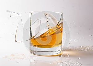 A shattering glass of brandy or brandy. Shards of glass and splashes of drink