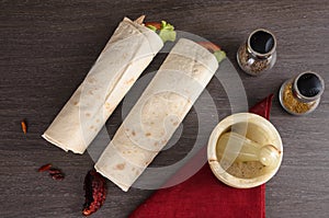 Shaurma chicken roll in a pita with fresh vegetables and cream sauce composition on wooden background