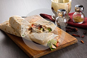 Shaurma chicken roll in a pita with fresh vegetables and cream sauce composition on wooden background