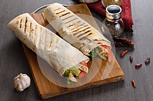 Shaurma chicken roll in a pita with fresh vegetables and cream sauce composition on wooden background