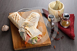 Shaurma chicken roll in a pita with fresh vegetables and cream sauce composition on wooden background