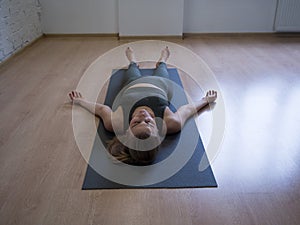 The shavasana. Woman laying on mat in relaxing pose on the floor, yoga class, front view photo