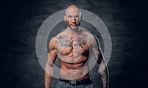 Shaved head, muscular male with tattoos on his torso over grey v