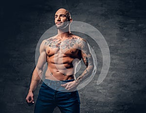 Shaved head, muscular male with tattoos on his torso over grey v